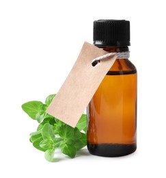 Essential oil in bottle with empty tag and oregano leaves isolated on white