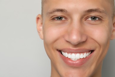 Photo of Happy young man on gray background, closeup. Dental veneers