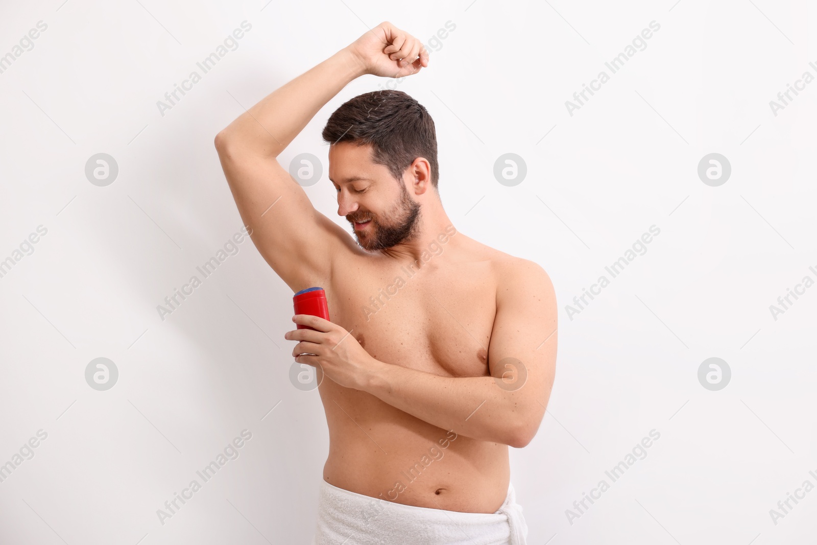 Photo of Handsome man applying solid deodorant on white background