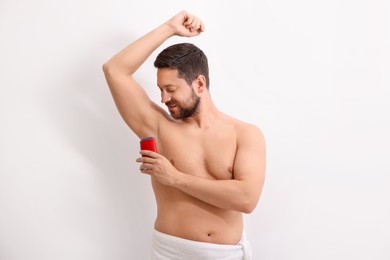 Photo of Handsome man applying solid deodorant on white background