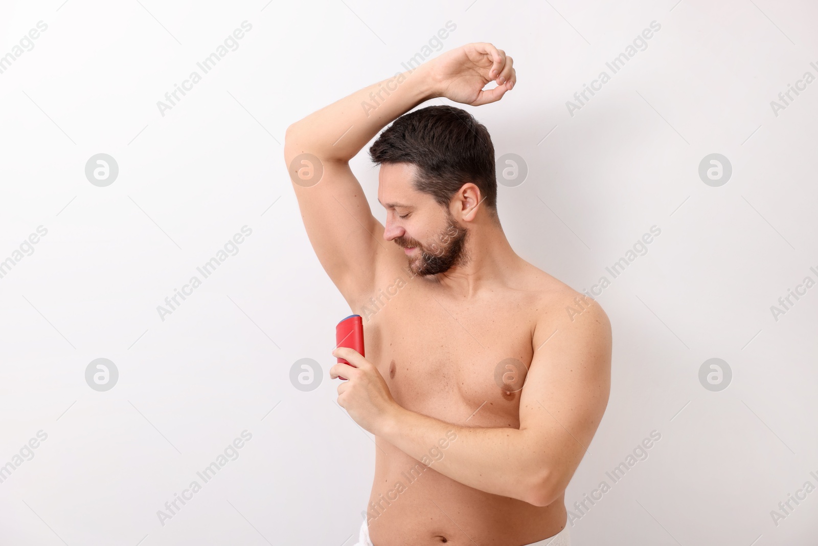 Photo of Handsome man applying solid deodorant on white background