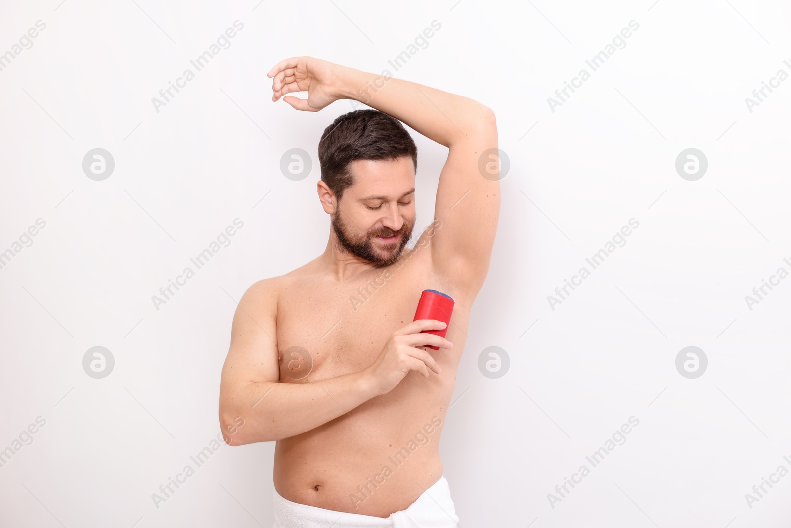 Photo of Handsome man applying solid deodorant on white background