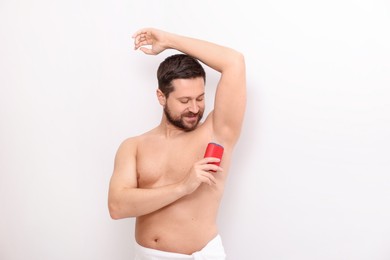 Photo of Handsome man applying solid deodorant on white background