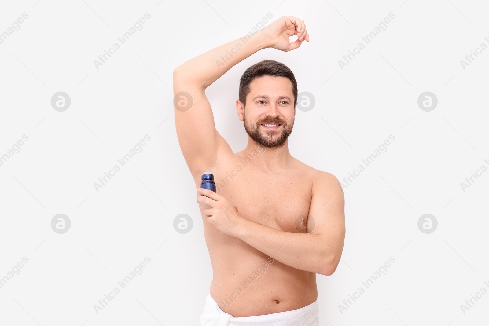 Photo of Smiling man applying roll-on deodorant on white background