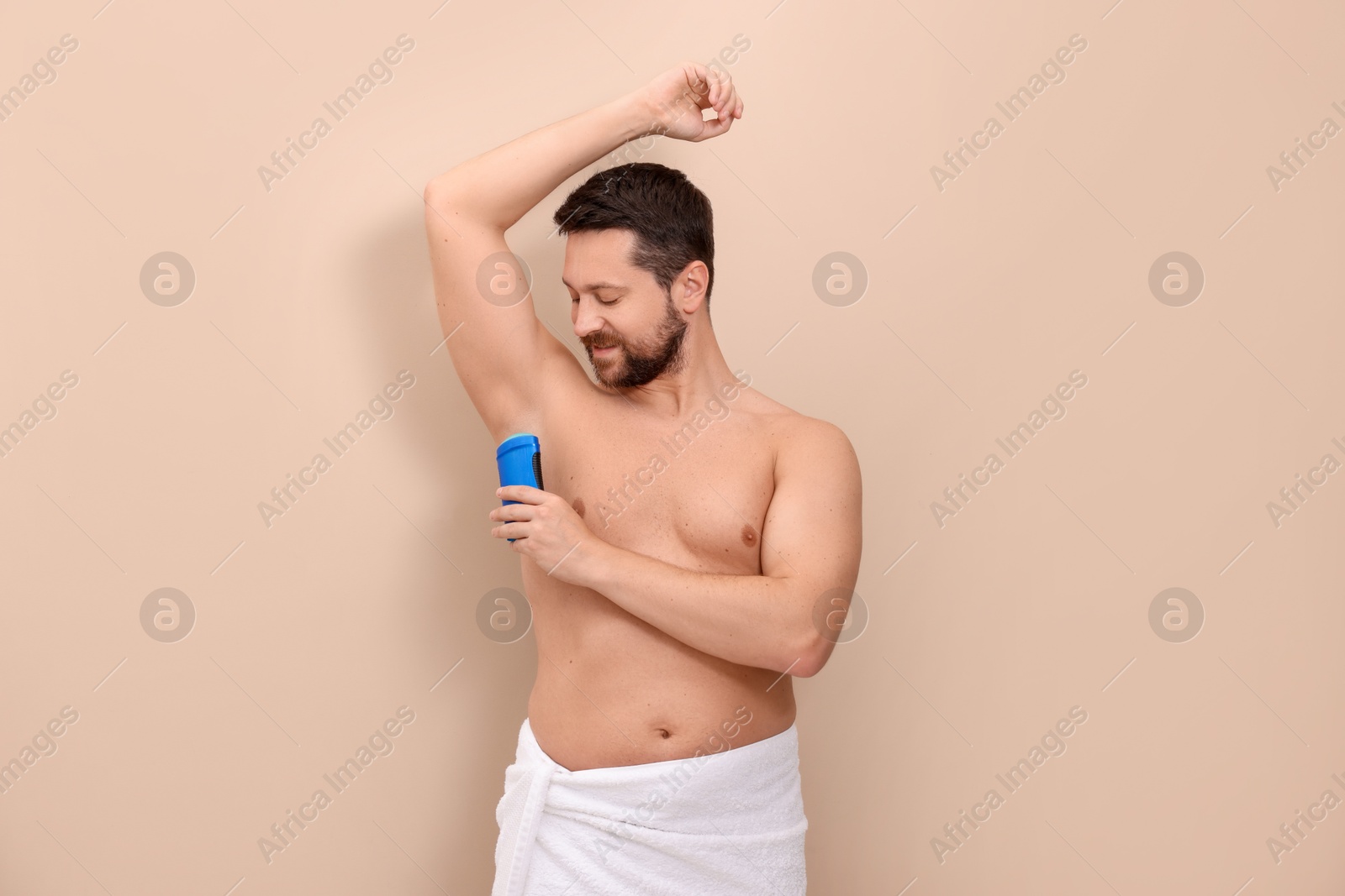 Photo of Man applying solid deodorant on beige background