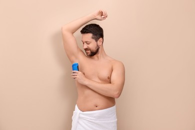 Man applying solid deodorant on beige background