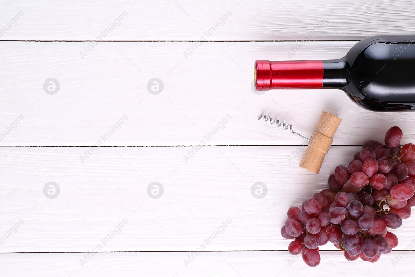 Photo of Corkscrew, bottle of wine and grapes on white wooden table, flat lay. Space for text