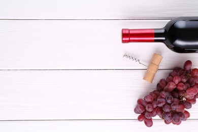 Photo of Corkscrew, bottle of wine and grapes on white wooden table, flat lay. Space for text