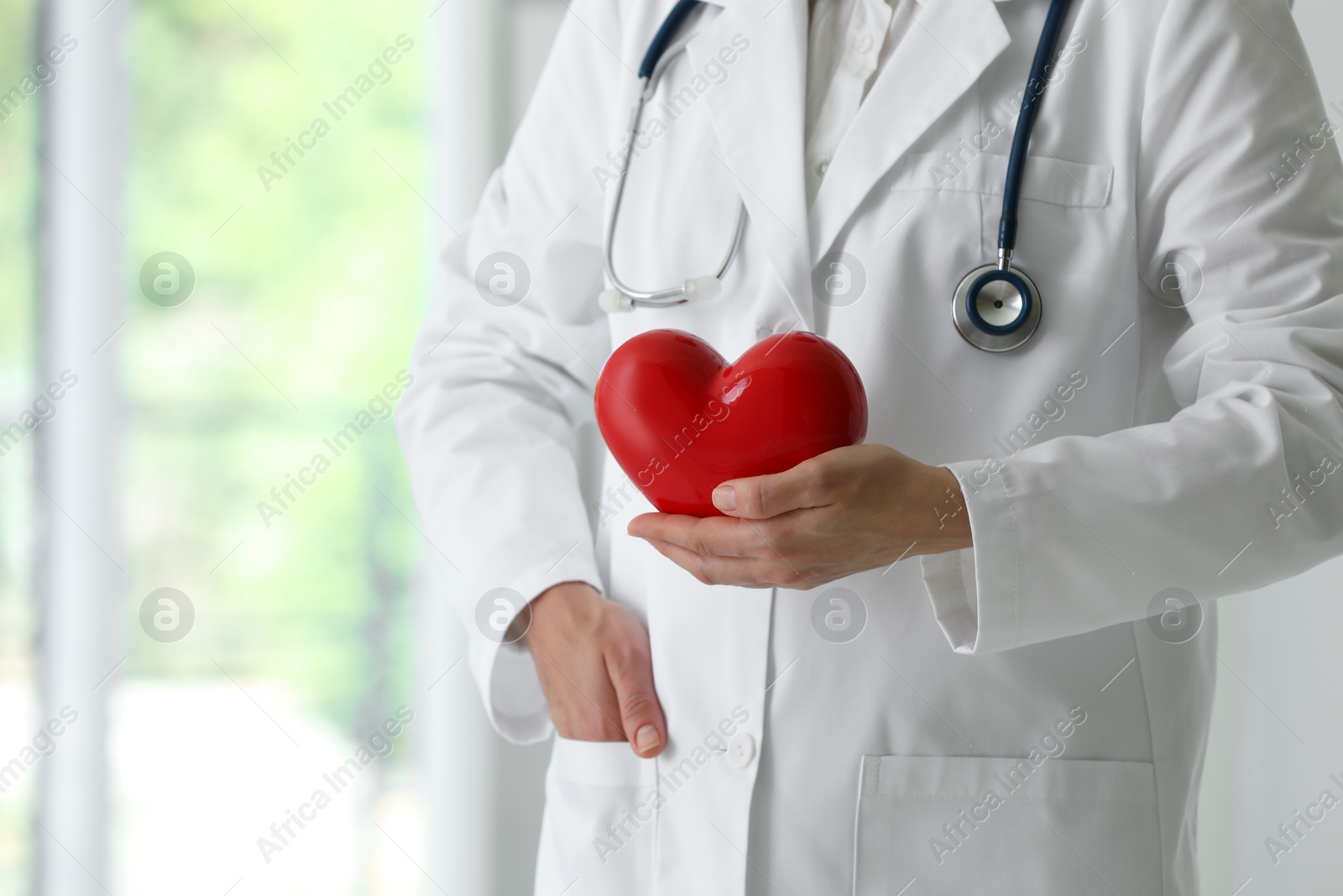 Photo of Doctor with red heart in clinic, closeup. Space for text