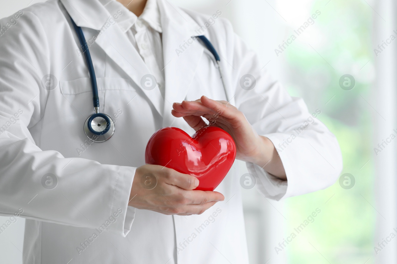 Photo of Doctor with red heart in clinic, closeup