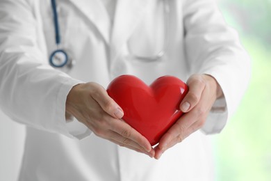 Photo of Doctor with red heart in clinic, closeup