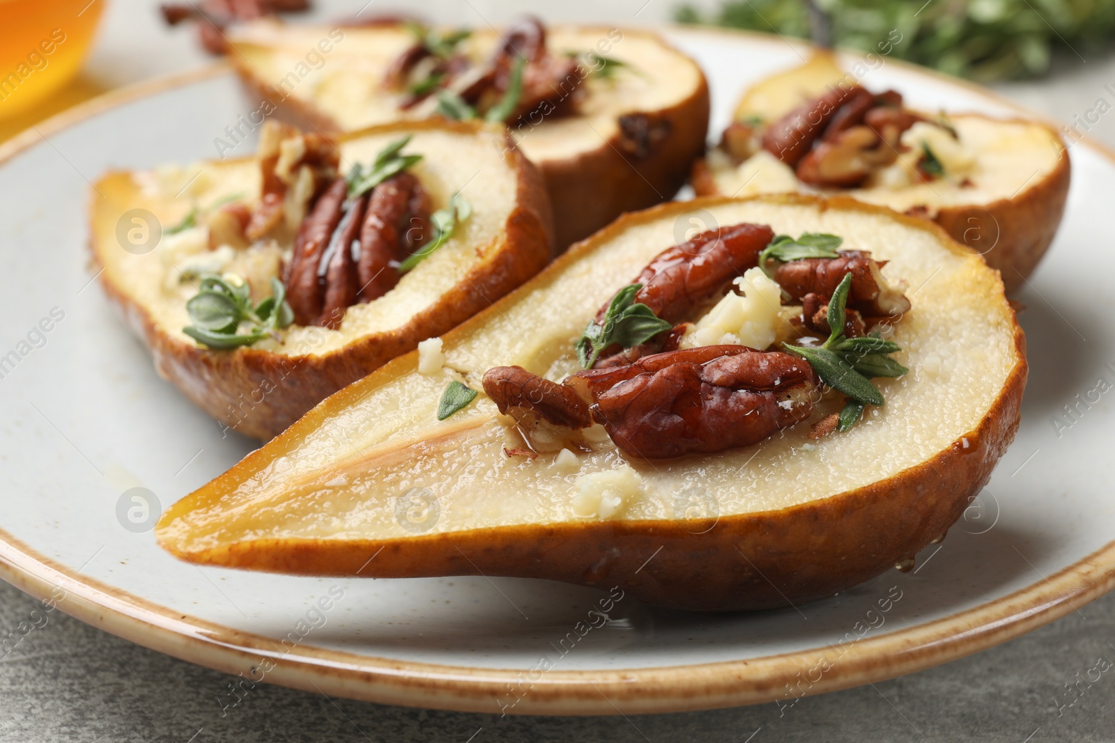 Photo of Tasty baked pears with nuts, blue cheese, thyme and honey on table, closeup