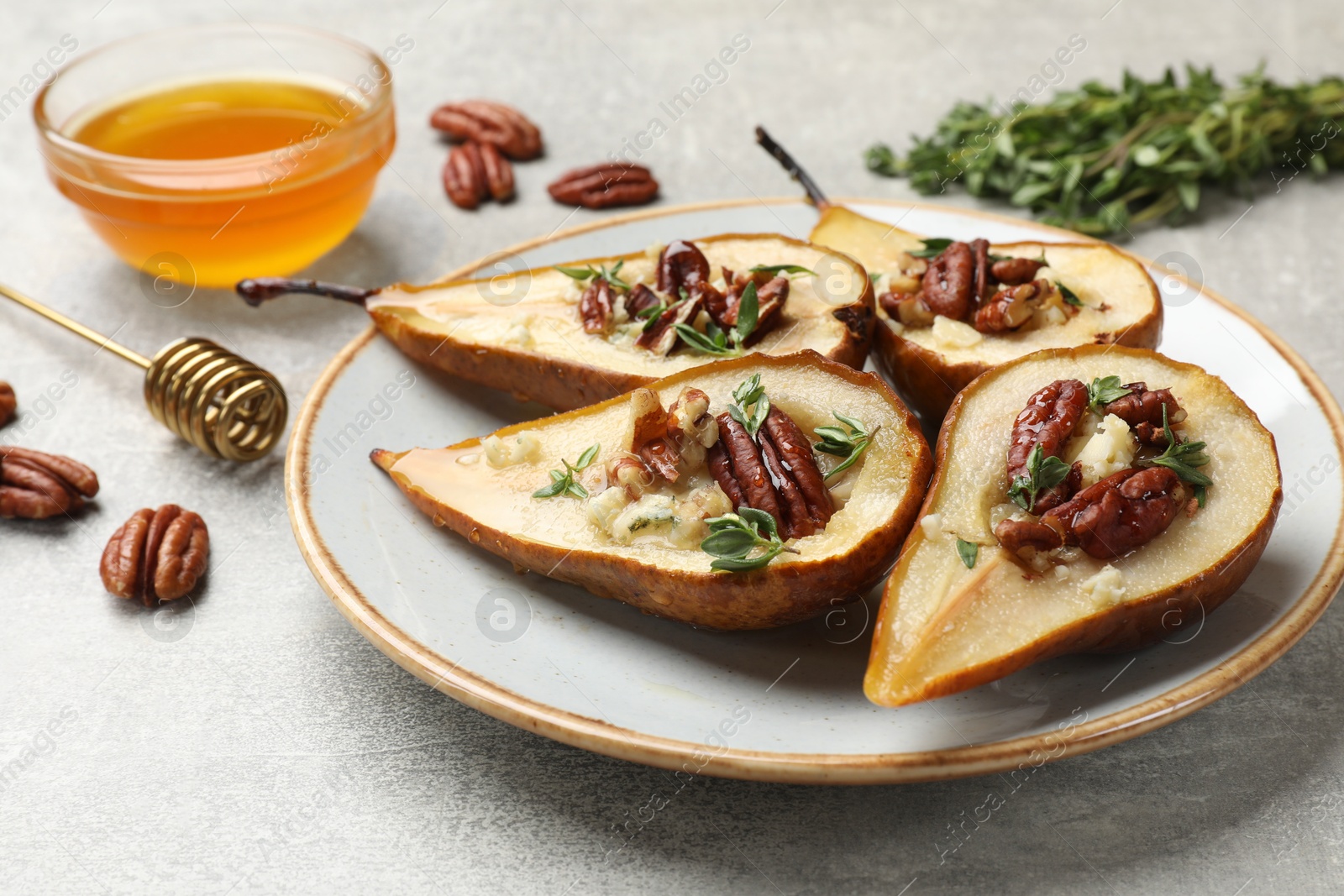 Photo of Tasty baked pears with nuts, blue cheese, thyme and honey on light grey table