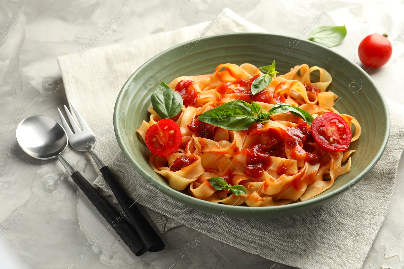 Photo of Delicious pasta with tomato sauce and basil served on grey textured table, closeup