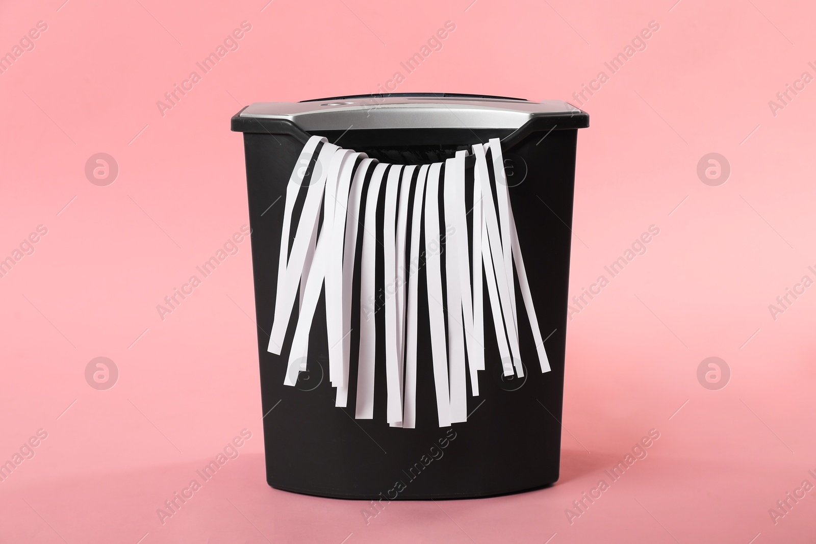 Photo of Shredder with paper strips on pink background