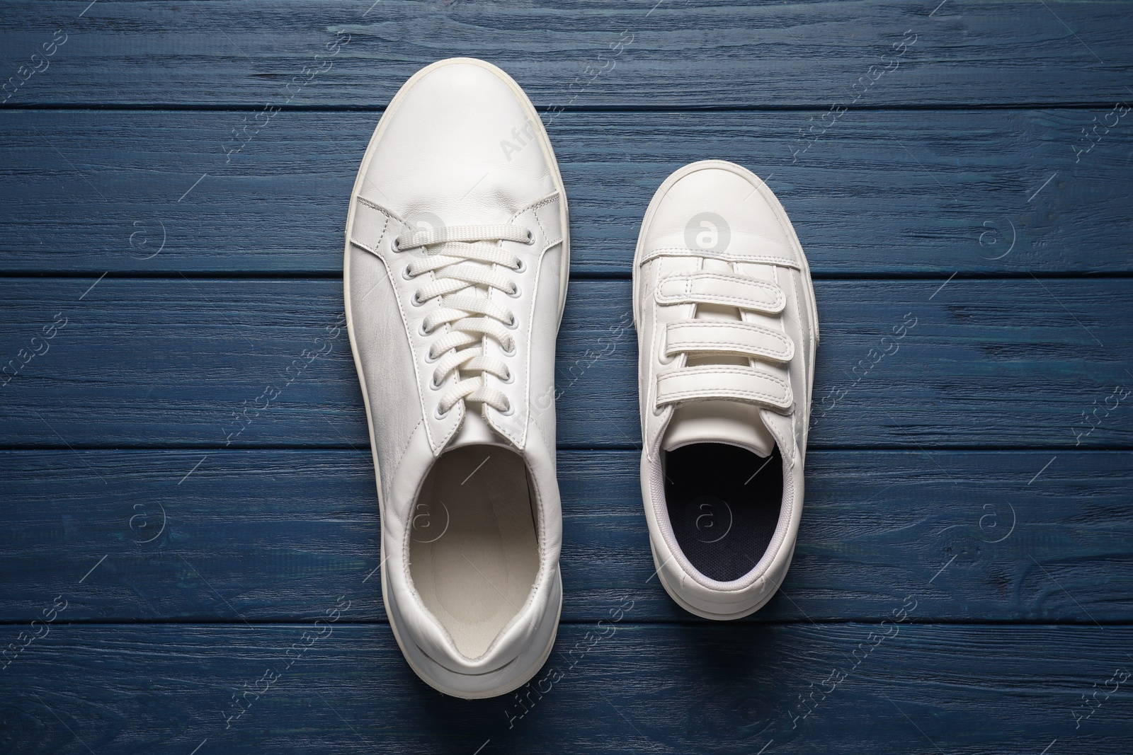 Photo of Big and small shoes on blue wooden table, top view