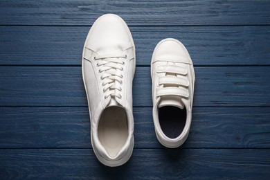 Big and small shoes on blue wooden table, top view