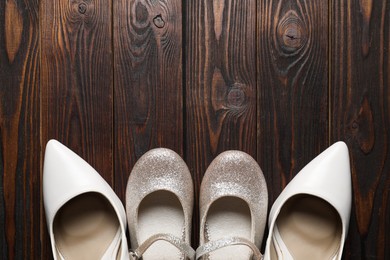 Photo of Big and small shoes on wooden table, top view. Space for text