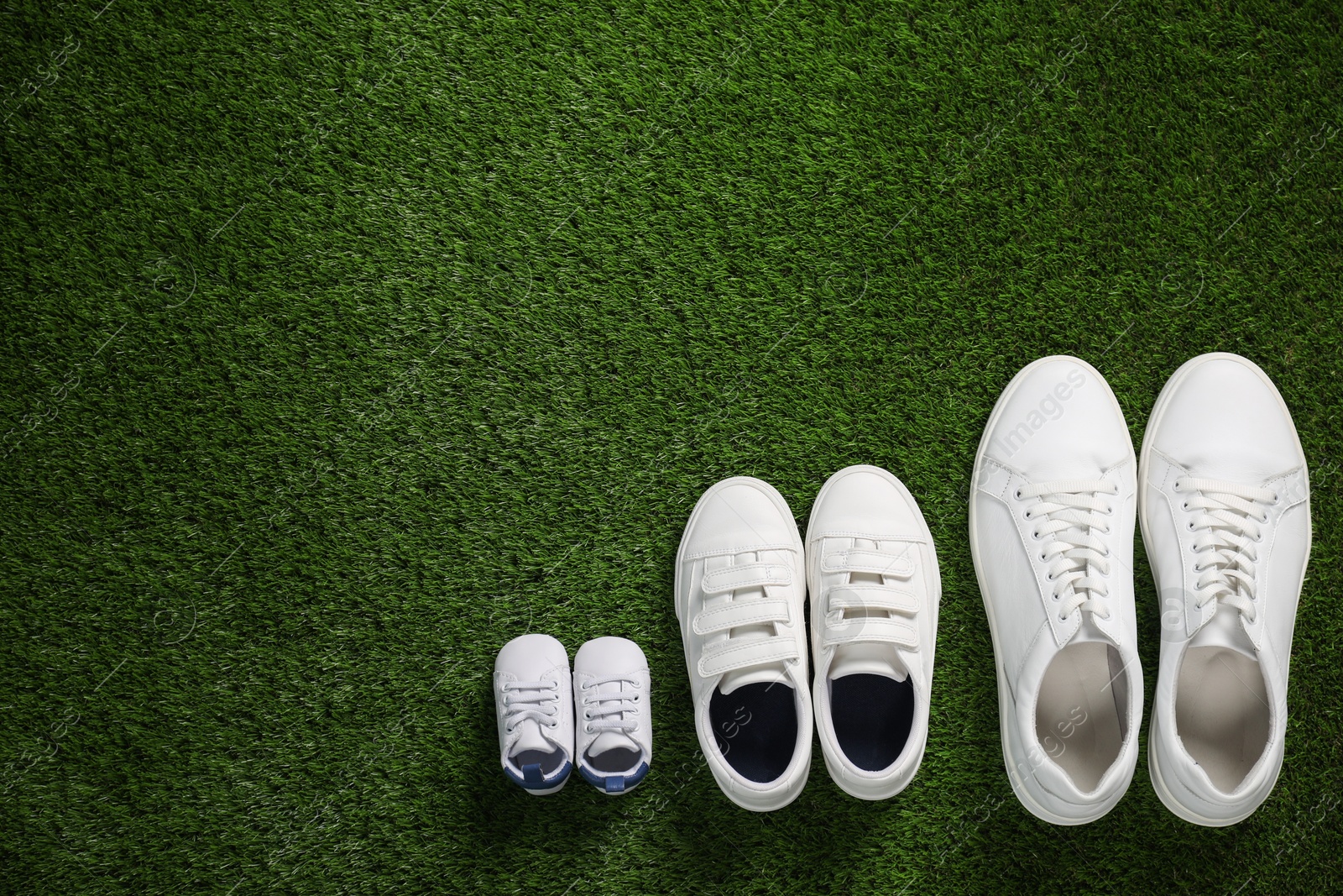 Photo of Big and small shoes on green grass, top view. Space for text