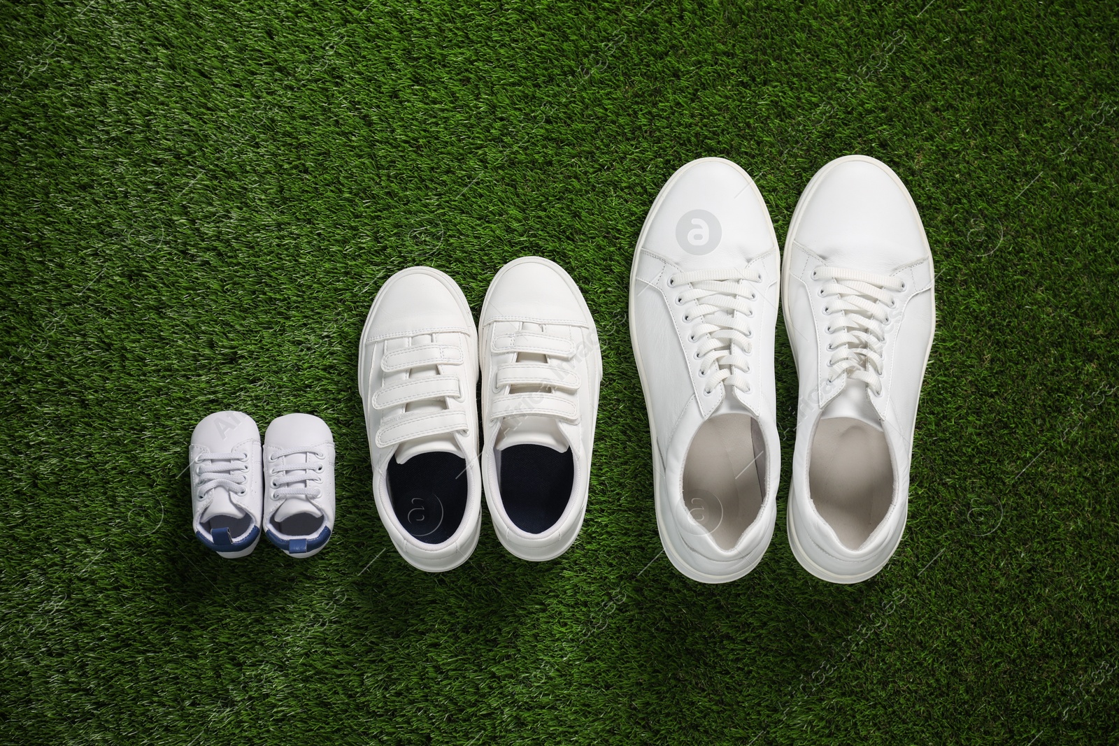 Photo of Big and small shoes on green grass, top view