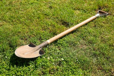 Photo of One rusty shovel on green grass. Gardening season