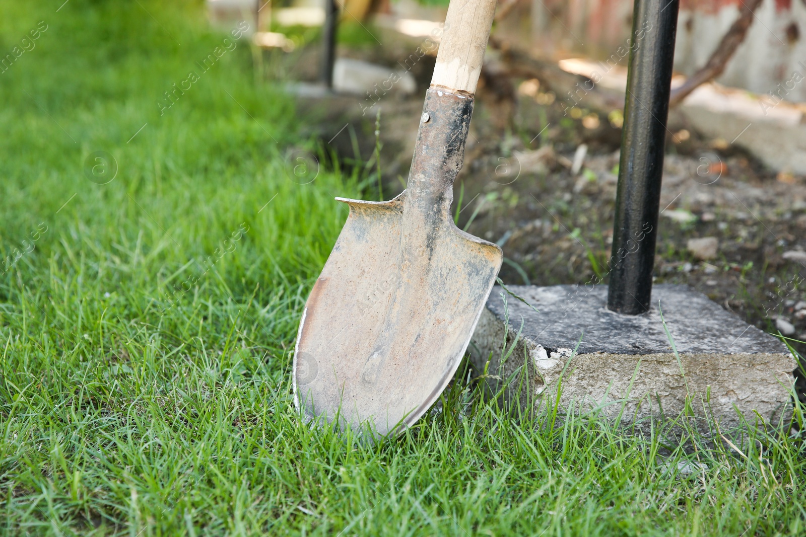 Photo of One rusty shovel on green grass in garden