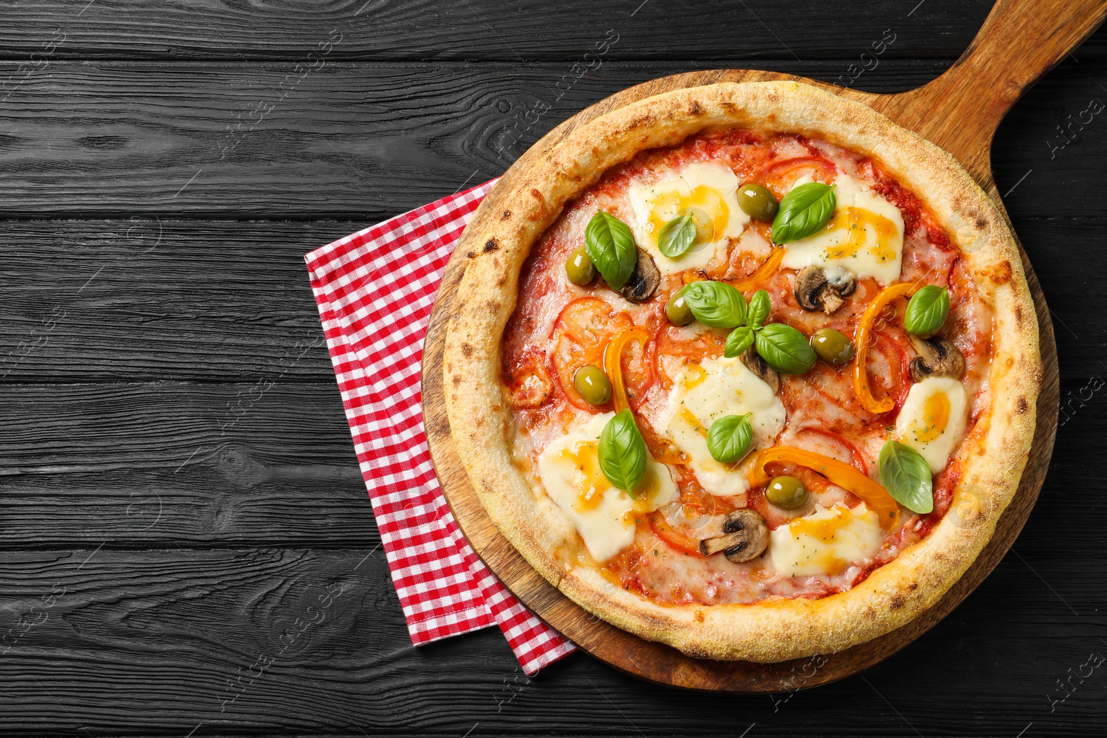 Photo of Delicious vegetarian pizza on black wooden table, top view