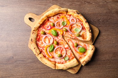 Photo of Cut delicious vegetarian pizza on wooden table, top view