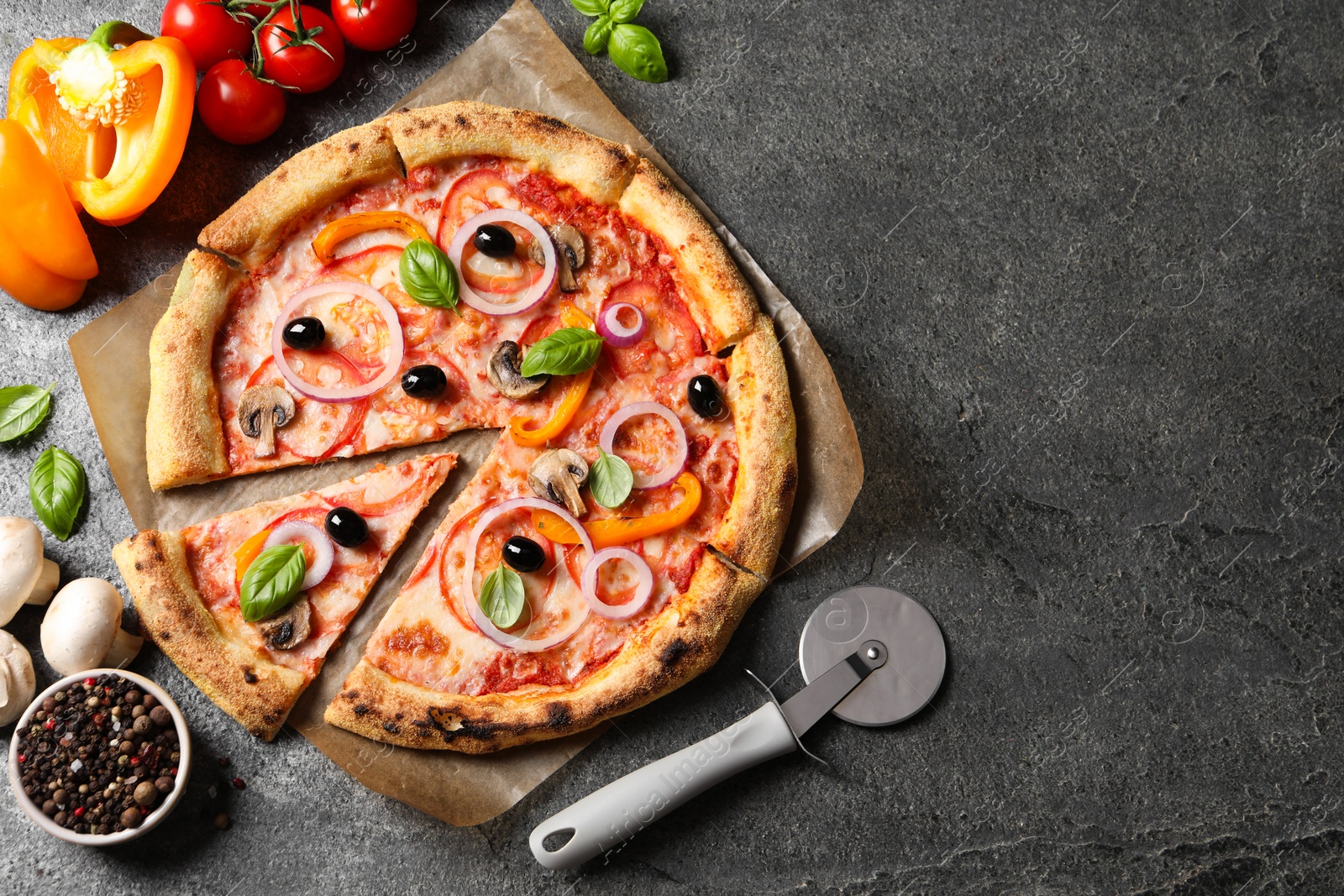 Photo of Cut delicious vegetarian pizza and ingredients on grey table, flat lay