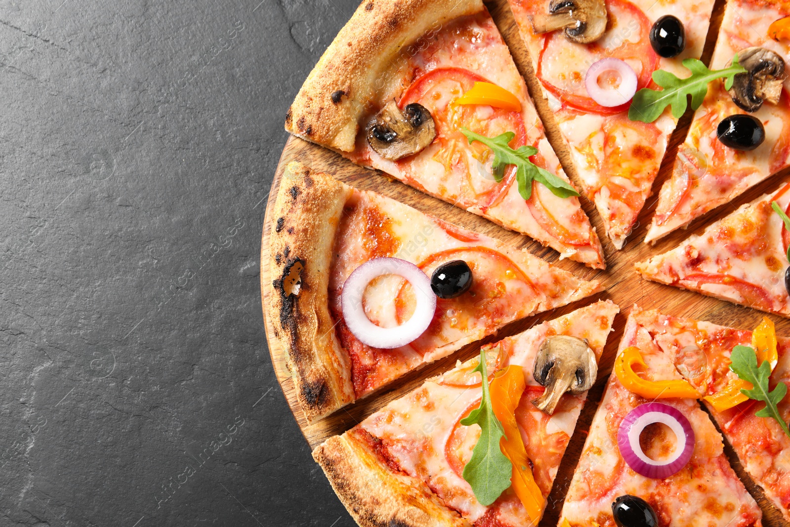 Photo of Cut delicious vegetarian pizza on black table, top view