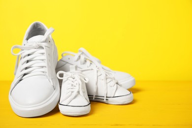 Photo of Big and small sneakers on yellow background. Space for text