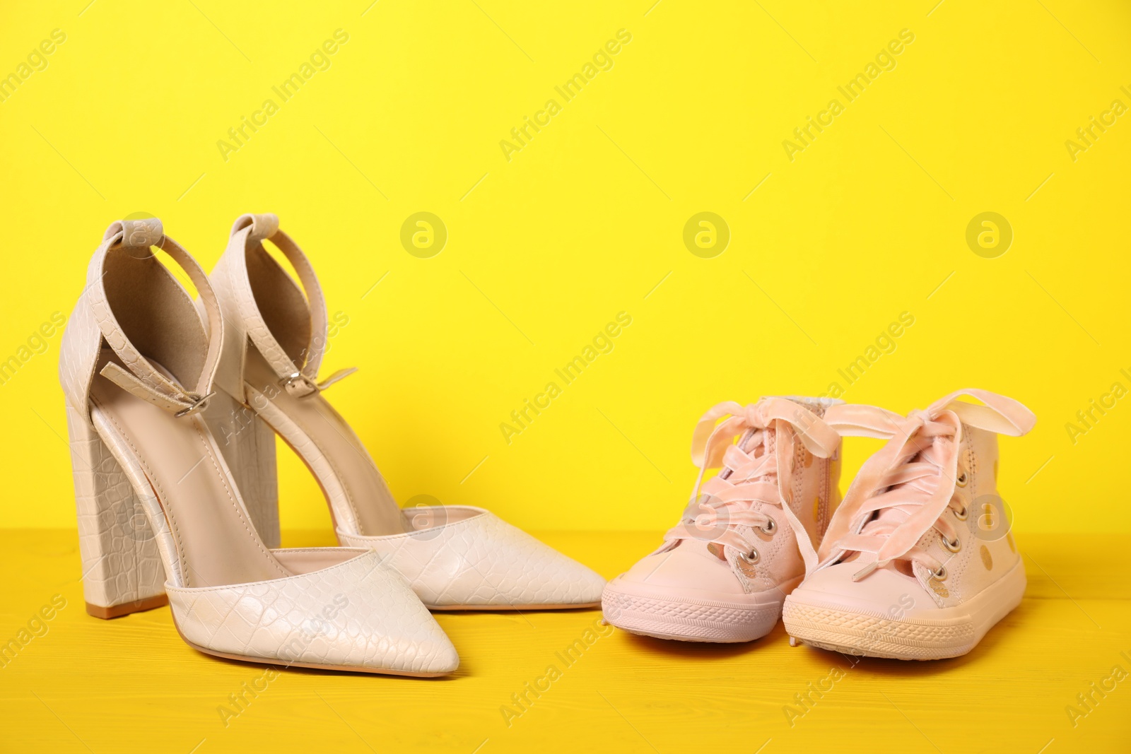 Photo of Big and small shoes on yellow background