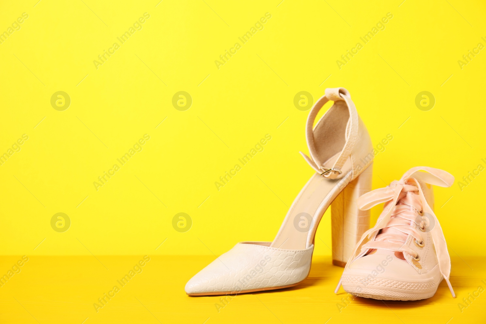 Photo of Big and small shoes on yellow background. Space for text