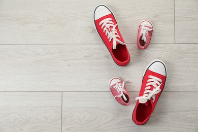 Photo of Big and small sneakers on floor, flat lay. Space for text