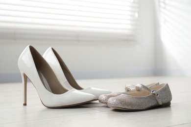 Photo of Big and small shoes on floor indoors