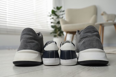 Photo of Big and small sneakers on floor indoors