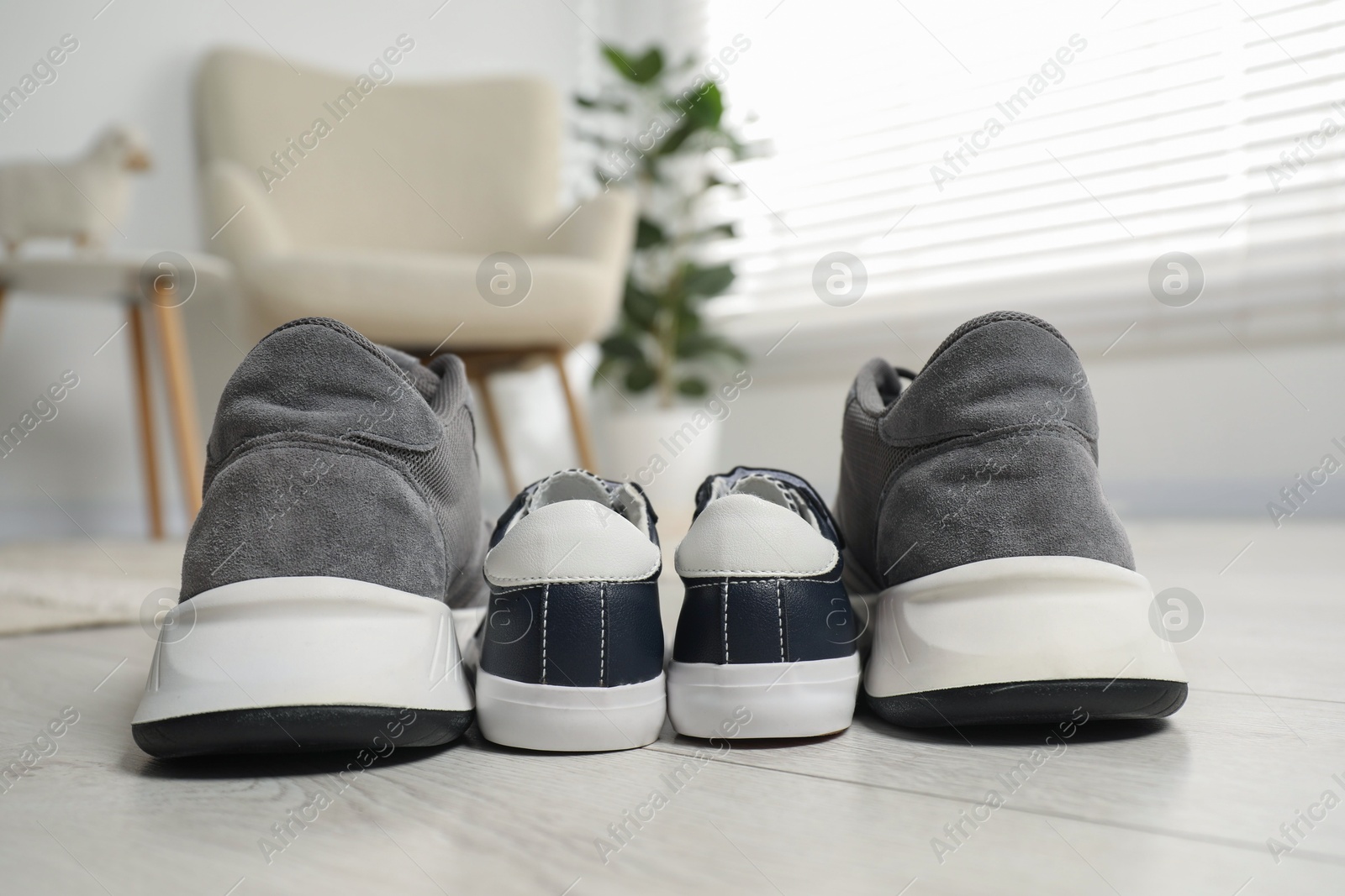 Photo of Big and small sneakers on floor indoors