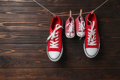 Big and small sneakers hanging on wooden background