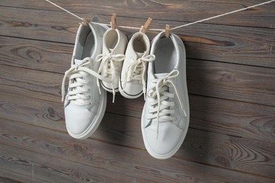 Photo of Big and small sneakers hanging on wooden background