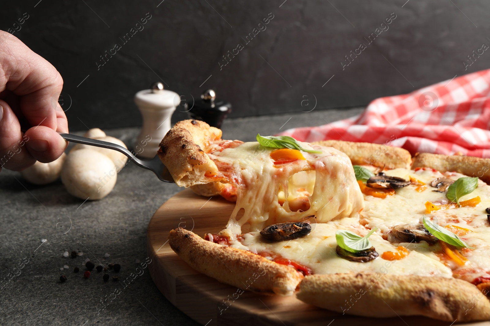 Photo of Man taking piece of delicious vegetarian pizza at grey table, closeup