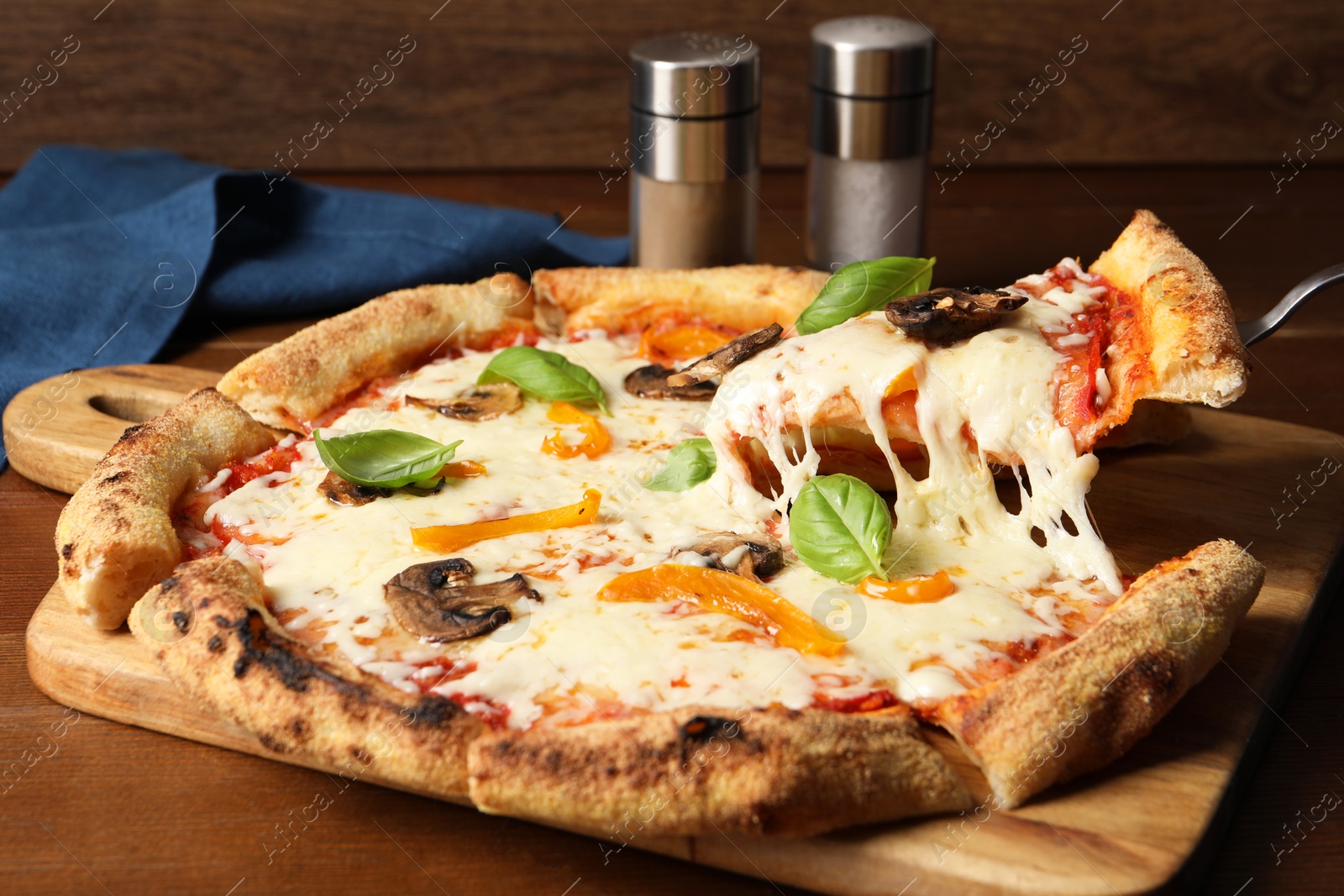 Photo of Taking piece of delicious vegetarian pizza at wooden table, closeup