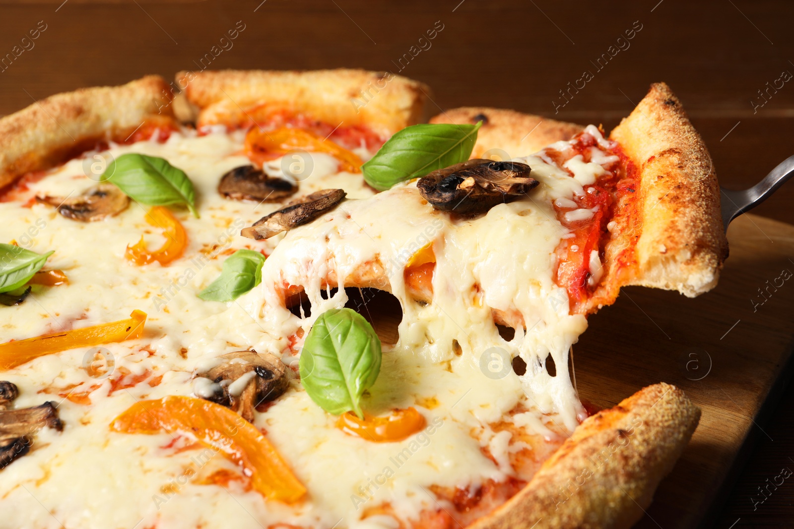 Photo of Taking piece of delicious vegetarian pizza at table, closeup