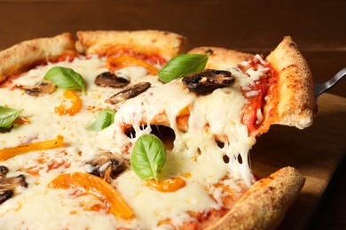 Photo of Taking piece of delicious vegetarian pizza at table, closeup