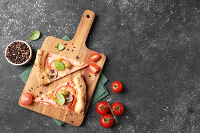 Photo of Cut delicious vegetarian pizza, spices and tomatoes on grey table, top view. Space for text