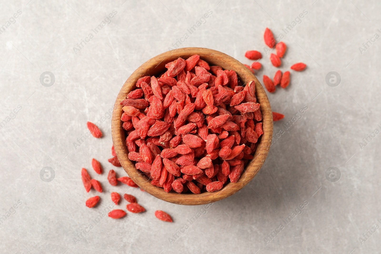 Photo of Dried goji berries in bowl on light grey table, top view