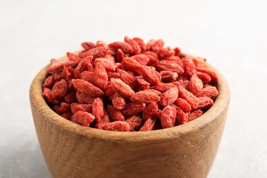 Dried goji berries in bowl on light grey table, closeup