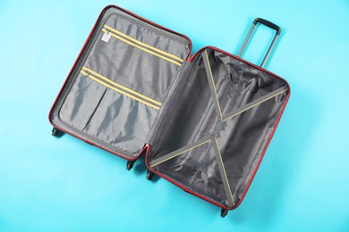 Photo of Open empty suitcase for travelling on light blue background, top view