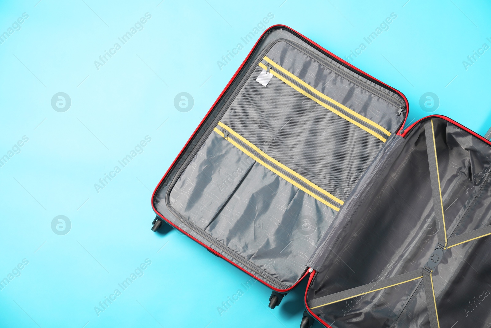 Photo of Open empty suitcase on light blue background, top view. Space for text