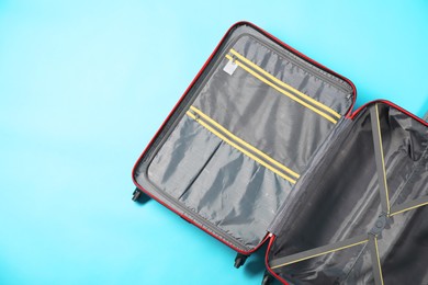 Photo of Open empty suitcase on light blue background, top view. Space for text