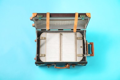 Photo of Open empty suitcase for travelling on light blue background, top view